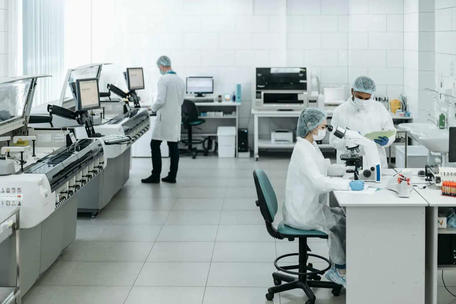 Researchers in lab coats performing experiments with advanced equipment in a laboratory.